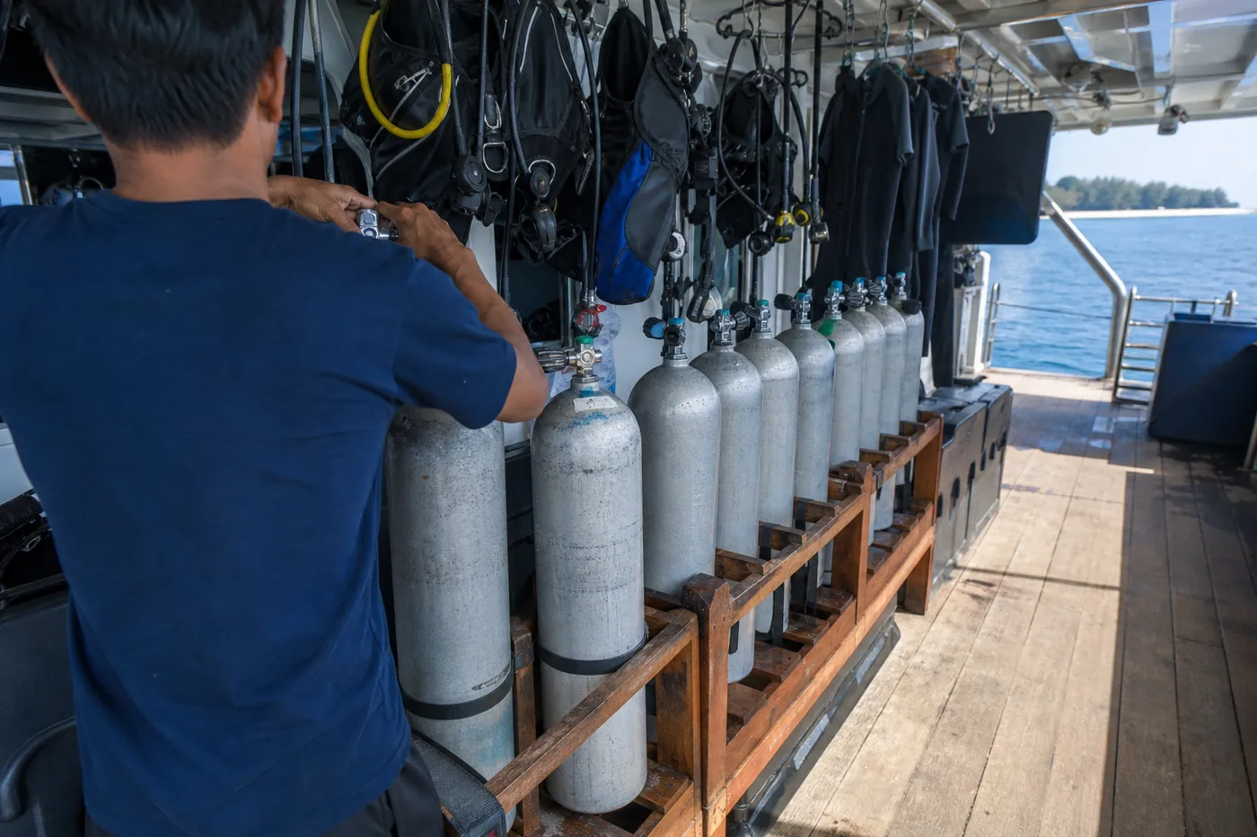 Divers preparing scuba tanks and equipment on the dive deck of an Indonesian liveaboard