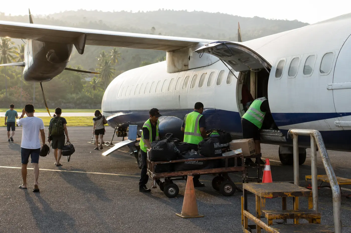 Ground crew loading dive bags into a regional turboprop at a small Indonesian airport on the domestic leg to Sorong