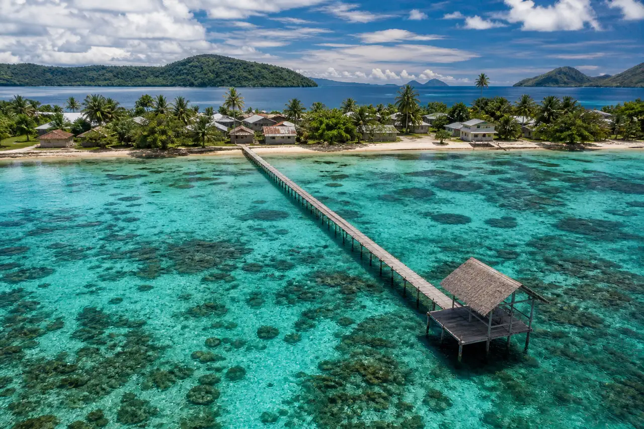 Wooden jetty at Arborek village in the Dampier Strait, Raja Ampat, with turquoise shallow water and forested islands behind